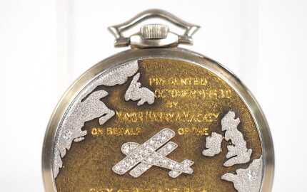 Le verso de cette montre de poche Longines, en or bicolore sablé, présente une inscription gravée. 